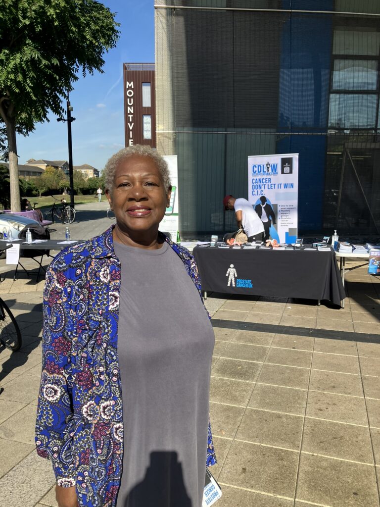 A woman stands in front of the health fair stand. 