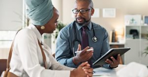 Conversation, healthcare or tablet with doctor and patient in office of hospital for consulting or insurance. Explain, medical and tech with medicine professional man speaking to person in clinic