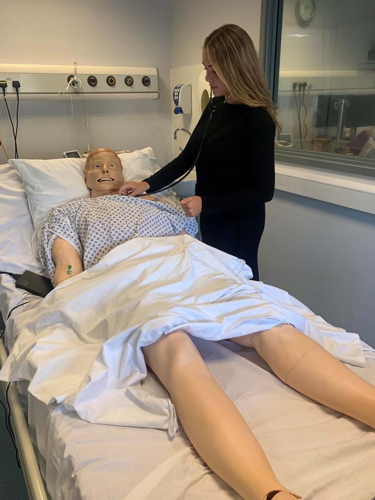 A woman, Perri Hanscombe, checking a 'medical dummy' in a bed
