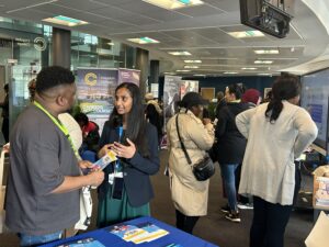 Two people in animated conversation at a stand in the South East London and South West London Joint Careers Fair.