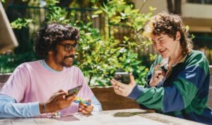 Two friends sitting outside and laughing at their phones